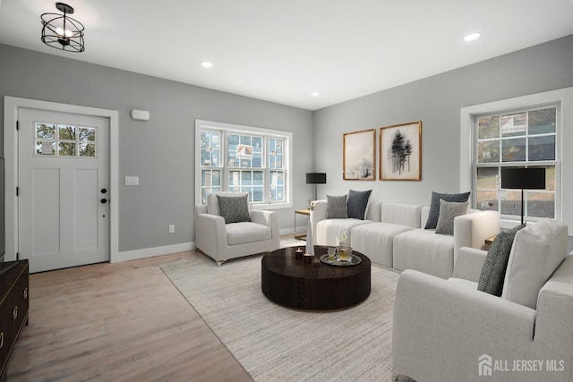 living room featuring a notable chandelier, a healthy amount of sunlight, and light wood-type flooring