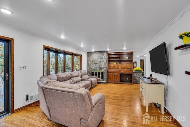 living room featuring a fireplace, ornamental molding, and light hardwood / wood-style flooring