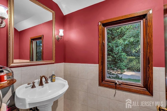 bathroom with tile walls, vaulted ceiling, and sink