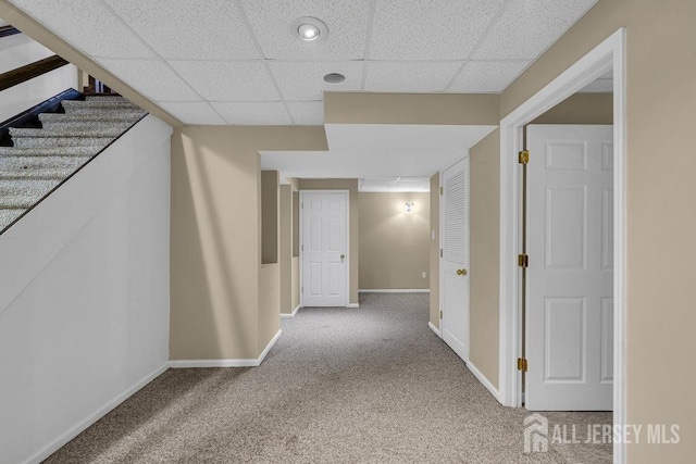 hallway with carpet floors and a drop ceiling