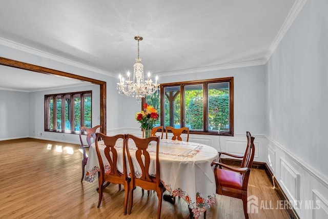 dining area with an inviting chandelier, ornamental molding, and light hardwood / wood-style floors