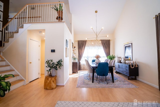 dining area featuring a high ceiling, a notable chandelier, and light hardwood / wood-style flooring