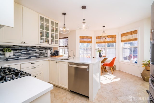 kitchen featuring a healthy amount of sunlight, hanging light fixtures, tasteful backsplash, and dishwasher