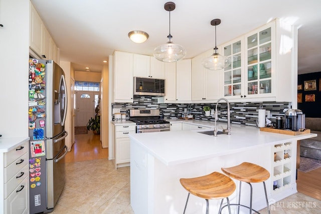 kitchen featuring sink, a breakfast bar, stainless steel appliances, white cabinets, and kitchen peninsula