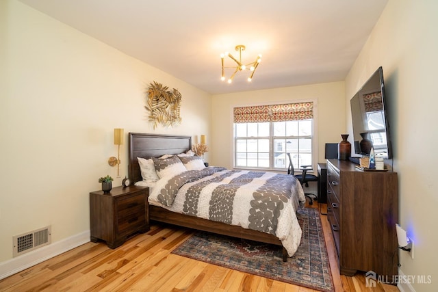 bedroom with an inviting chandelier and light hardwood / wood-style flooring