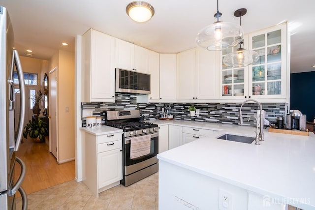 kitchen with sink, decorative light fixtures, stainless steel appliances, and white cabinets