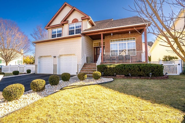 view of property featuring a garage, a front yard, and a porch