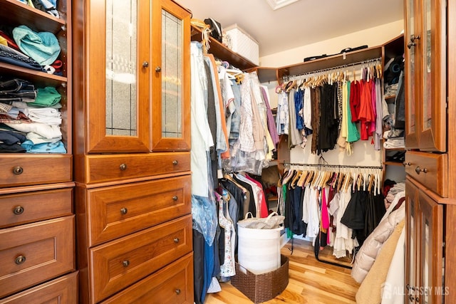 walk in closet with light hardwood / wood-style floors