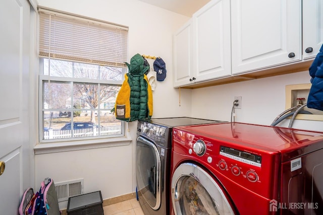 washroom with cabinets, washer and clothes dryer, and light tile patterned floors