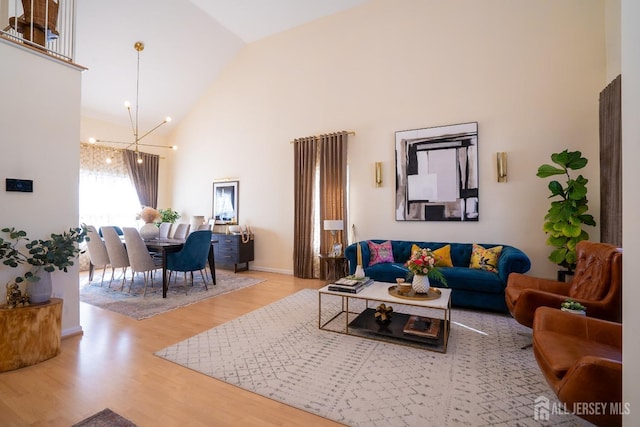 living room featuring a chandelier, high vaulted ceiling, and light hardwood / wood-style flooring