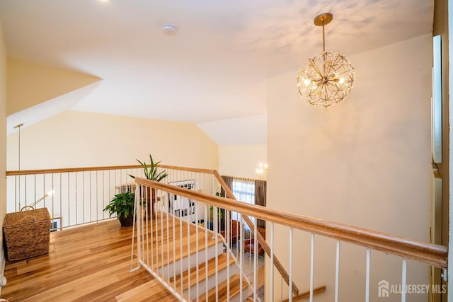 corridor featuring lofted ceiling, a chandelier, and wood-type flooring