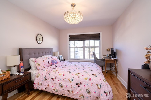 bedroom with light hardwood / wood-style flooring and a chandelier