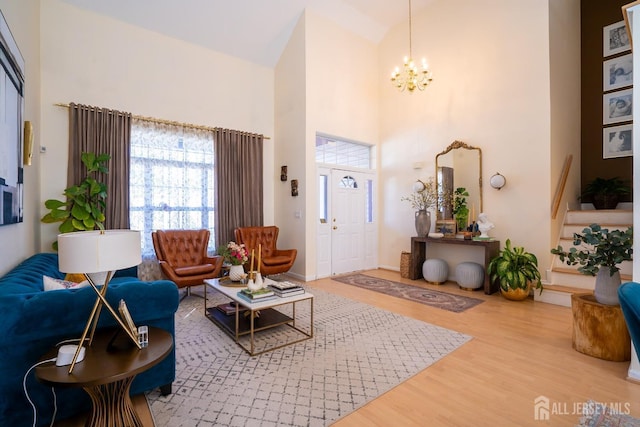 living room with hardwood / wood-style floors, a towering ceiling, and a chandelier