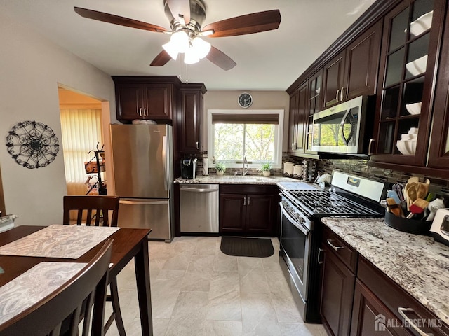 kitchen with dark brown cabinetry, light stone countertops, ceiling fan, and stainless steel appliances