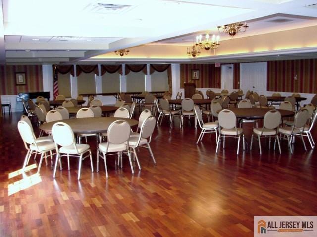 dining area with wood finished floors, visible vents, and an inviting chandelier