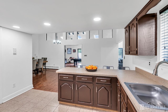 218 Community Cir, Old Bridge, NJ 08857 - kitchen with a sink, dark brown cabinetry, a baseboard radiator, a peninsula, and light countertops