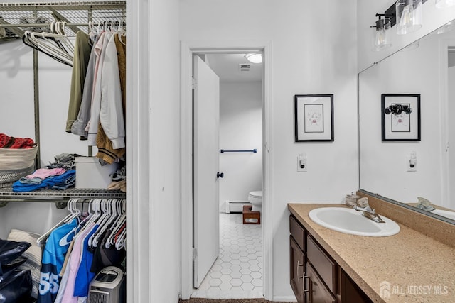 218 Community Cir, Old Bridge, NJ 08857 - bathroom featuring vanity, a baseboard heating unit, toilet, and a walk in closet
