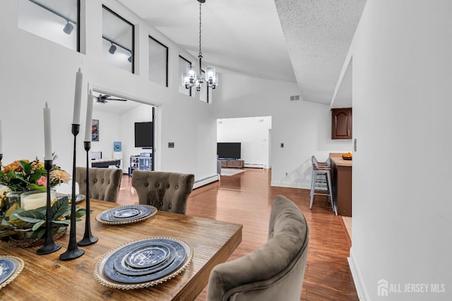 218 Community Cir, Old Bridge, NJ 08857 - dining area with a chandelier, a baseboard radiator, wood finished floors, a baseboard heating unit, and high vaulted ceiling