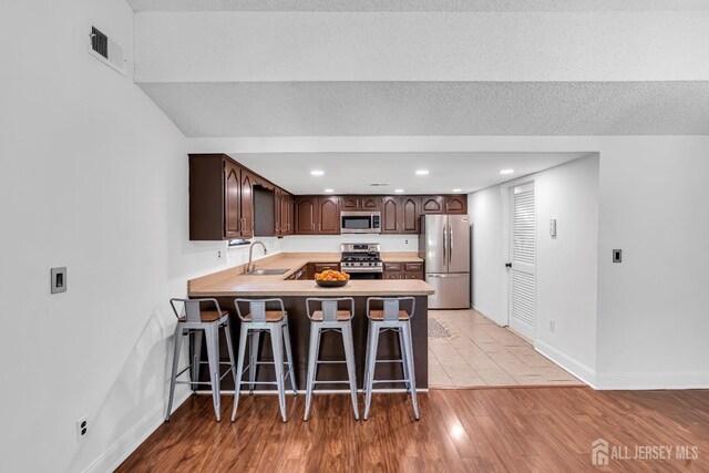 218 Community Cir, Old Bridge, NJ 08857 - kitchen featuring appliances with stainless steel finishes, a sink, dark brown cabinets, baseboards, and a peninsula