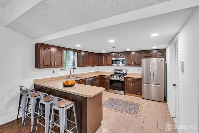 218 Community Cir, Old Bridge, NJ 08857 - kitchen featuring stainless steel appliances, dark brown cabinetry, a sink, light countertops, and a peninsula