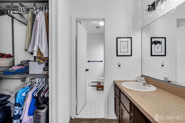218 Community Cir, Old Bridge, NJ 08857 - bathroom with a baseboard heating unit, vanity, toilet, and a spacious closet