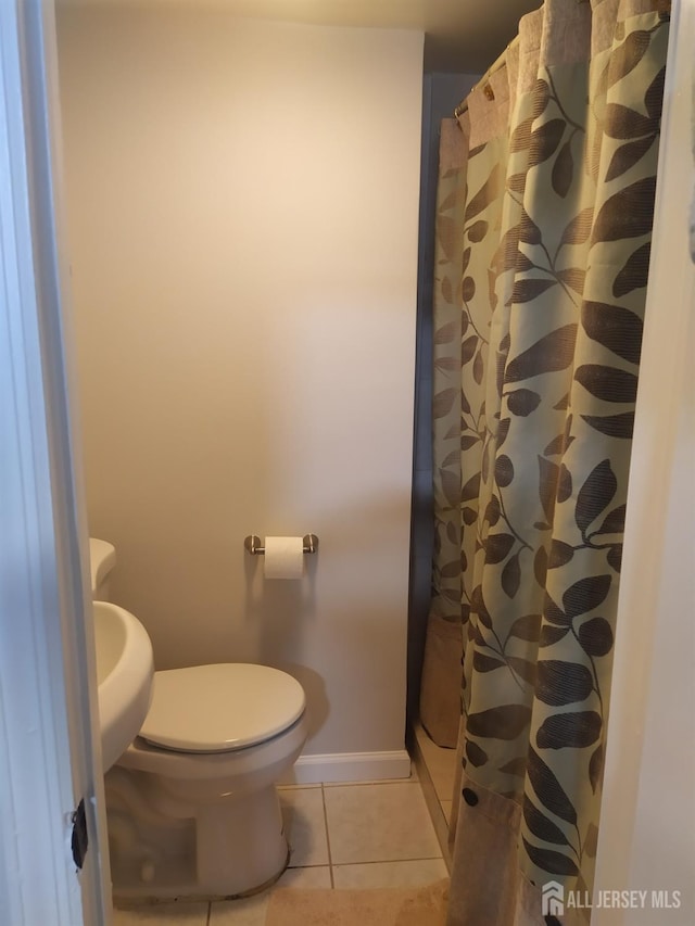 bathroom featuring curtained shower, tile patterned flooring, toilet, and baseboards