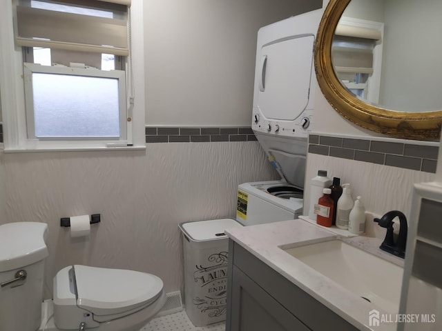 half bathroom featuring toilet, tile walls, and vanity