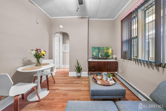 living area featuring baseboards, arched walkways, crown molding, light wood-type flooring, and a baseboard heating unit