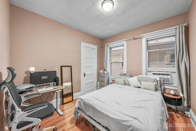 bedroom with baseboards, cooling unit, and light wood-style floors