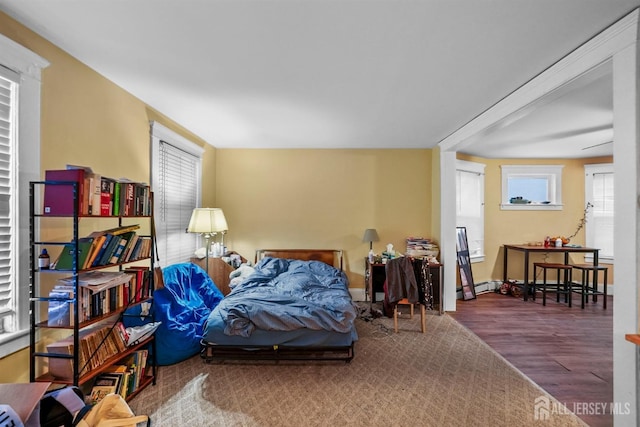 bedroom with a baseboard heating unit and wood finished floors