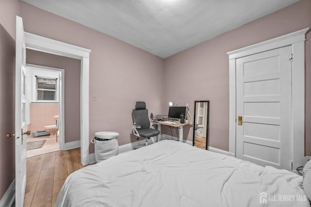 bedroom with baseboards, a baseboard radiator, connected bathroom, and light wood-style floors