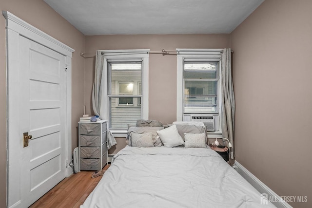 bedroom featuring cooling unit, baseboards, and wood finished floors