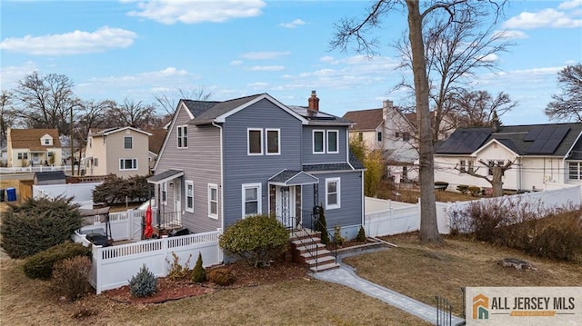 view of front of property with a residential view, a fenced backyard, and a chimney