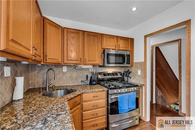2124 Orchard Dr, South Plainfield, NJ 07080 - kitchen with brown cabinetry, backsplash, appliances with stainless steel finishes, a sink, and stone counters