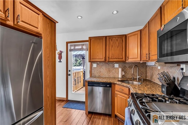 2124 Orchard Dr, South Plainfield, NJ 07080 - kitchen featuring brown cabinets, tasteful backsplash, a sink, light wood finished floors, and stainless steel appliances