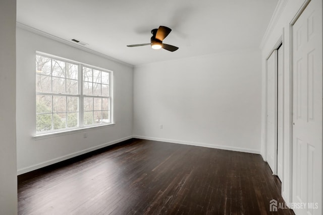 unfurnished bedroom featuring baseboards, ornamental molding, dark wood finished floors, ceiling fan, and visible vents