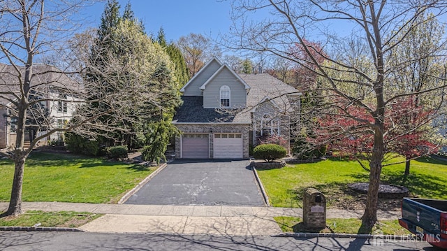 traditional-style house with a garage, a front yard, and driveway