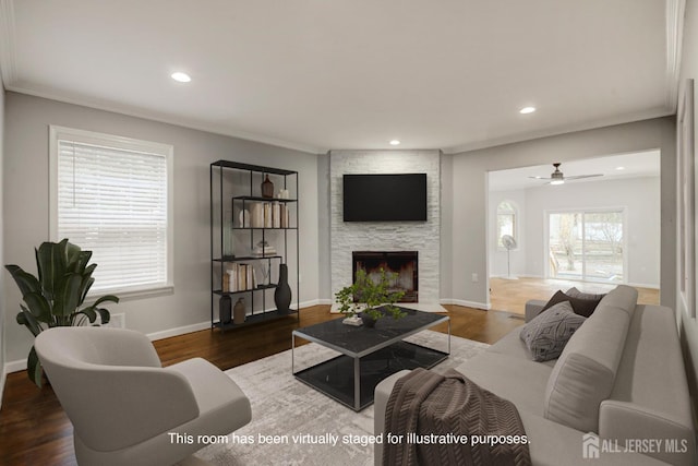 living room with a large fireplace, ornamental molding, wood finished floors, and recessed lighting