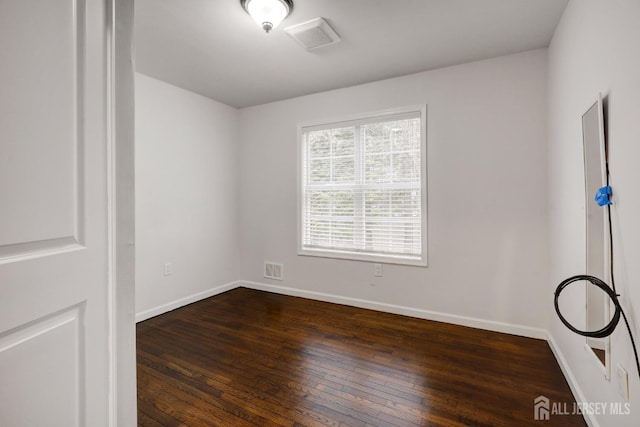 spare room with baseboards, dark wood finished floors, and visible vents