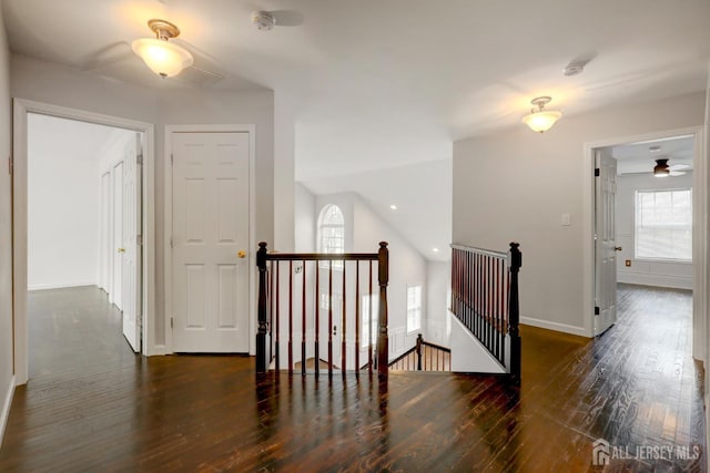 corridor with wood finished floors, an upstairs landing, baseboards, and lofted ceiling
