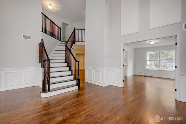 foyer with a wainscoted wall, visible vents, wood-type flooring, and stairway