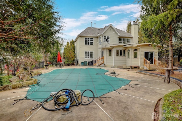 back of house featuring fence, entry steps, a patio area, and a chimney