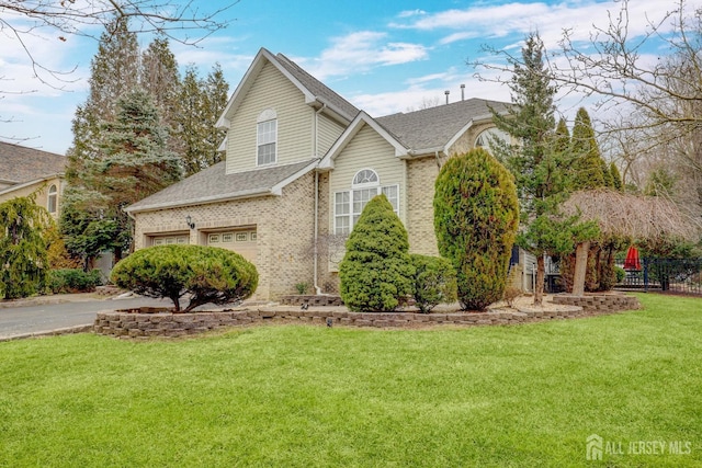 traditional-style home featuring a front lawn, driveway, brick siding, and a garage