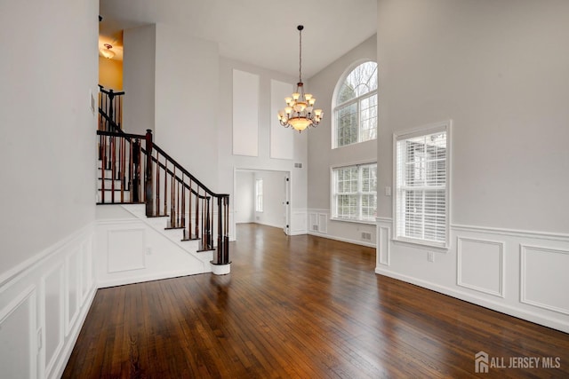 entrance foyer with stairway, a towering ceiling, a decorative wall, and a notable chandelier