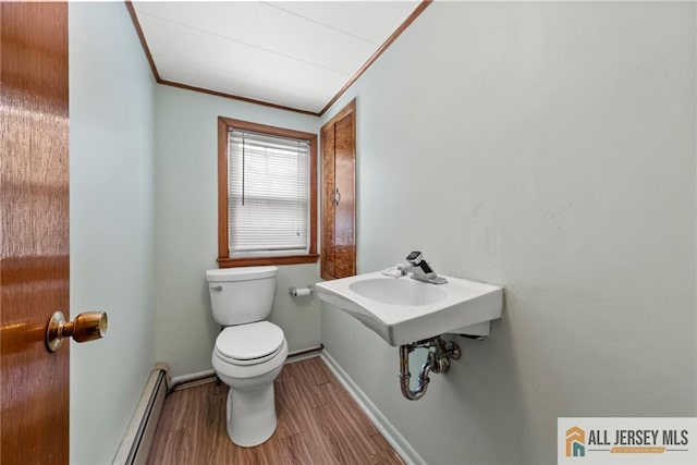 bathroom featuring a baseboard heating unit, toilet, crown molding, and wood-type flooring