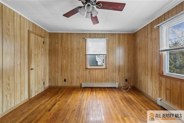 unfurnished room featuring a baseboard radiator, wood walls, ceiling fan, and wood-type flooring