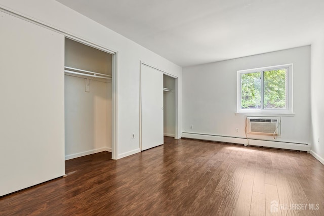 18 Lake Ave Unit 8A, East Brunswick, NJ 08816 - unfurnished bedroom featuring two closets, a baseboard radiator, wood finished floors, and a wall unit AC