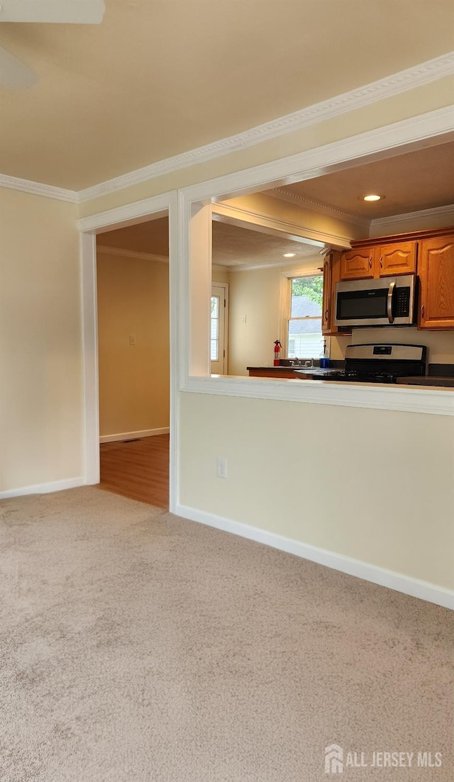 20 Brunswick Ave, Spotswood, NJ 08884 - kitchen with stainless steel appliances, brown cabinetry, ornamental molding, carpet floors, and dark countertops