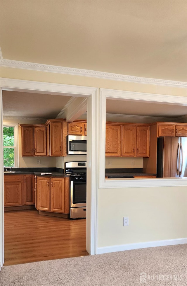 20 Brunswick Ave, Spotswood, NJ 08884 - kitchen featuring appliances with stainless steel finishes, brown cabinetry, dark countertops, carpet floors, and crown molding