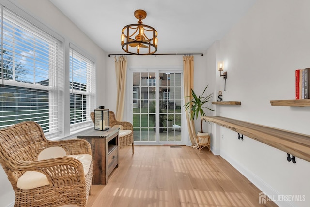 living area featuring baseboards, a chandelier, and light wood-type flooring
